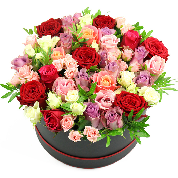 A sophisticated black cylindrical hatbox, accented delicately with a thin red band at its base, serves as the foundation for this rich, rose-filled arrangement, photographed crisply against a clean white backdrop. The hatbox has a smooth, matte finish that feels quietly luxurious, like a bespoke gift you might see carried along Grove Park Terrace. Above it, the roses are packed tightly into an opulent, dome-shaped bouquet, overflowing from the rim in a cascade of colour and texture. Deep crimson and scarlet roses are placed prominently, their velvety petals forming intricate spirals that draw the eye inward. These intense reds are softened by romantic fuchsia and blush pink roses, whose gentler tones create a graceful contrast. Warm coral and delicate peach blooms introduce a sun-kissed glow, while creamy white and ivory roses punctuate the composition, adding brightness and a sense of purity. Threaded throughout the arrangement are sophisticated lavender and muted purple roses, bringing a cool, modern elegance to the palette. The flowers are at different stages of opening; some roses are fully unfurled, displaying lush, cupped centres, while others remain in tighter buds, especially the spray roses that add a fine, almost lace-like detail to the design. Small sprigs of fresh green foliage-likely ruscus or another slender filler green-are nestled between the petals, bringing refreshing hints of verdant colour and helping to frame the blooms. The overall shape is a perfectly rounded dome, suggesting the careful eye and practiced hand of a skilled florist, perhaps at Grove Park Florist, accustomed to creating premium flower boxes for anniversaries, special birthdays, or elegant table pieces for dinner parties near the river. The impression is one of abundance, refinement, and heartfelt celebration.