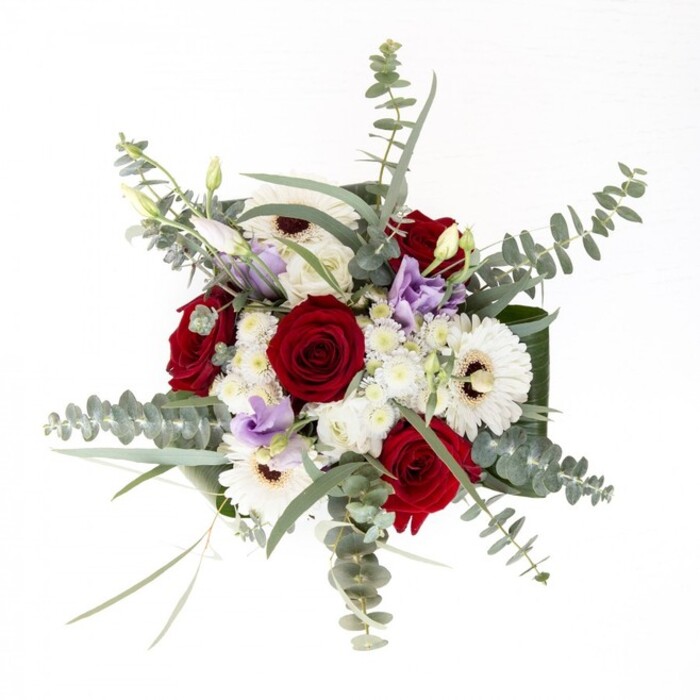 To describe this bouquet as a florist serving Grove Park is to evoke not just its lush physical form, but also its emotional resonance within our local community. Large, creamy gerberas serve as luminous foundations, each petal flawlessly fanned from a dark, coffee-brown center, while passionate red roses spiral with timeless appeal-symbols of love and remembrance cherished among neighbors. Whispers of lilac lisianthus, artfully placed, introduce a contemporary air, suggesting the changing light at dusk over nearby Chiswick gardens. The eucalyptus, with its round, silvery-sage leaves, adds height, cool undertones, and a clean scent, conjuring the feeling of a fresh morning in Grove Park. Beneath, broad dark green leaves curve in polished arcs, sculpting the bouquet's shape and offering a sense of invitation. Filler flowers, soft and white as first snow, scatter brightness through the composition and encourage touch. Water cradles the stems in the vase's clear embrace, a sign of freshness as though these blooms were just gathered from a local Grove Park market. Whether given in celebration, sympathy, or for everyday beauty, this bouquet reflects the warmth and reliability that Grove Park Florist strives to bring with every bespoke arrangement.