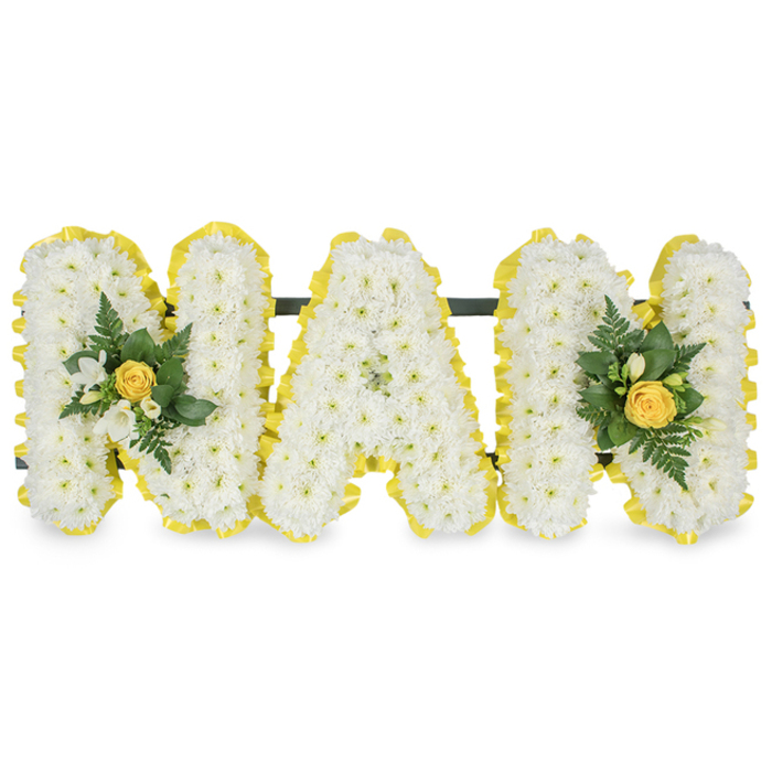 A personalised memorial tribute spelling out MAM, each capital letter meticulously formed from a dense field of small white chrysanthemum florets to achieve a soft, cloud-like texture across the face of every character. The perimeter of every letter is crisply finished with a bright, pleated yellow satin ribbon that wraps the edges with a neat, sunny definition, the pleats catching the light to create a slightly sculptural rim. Two elegant floral accents enhance the overall rhythm: one rests on the left upright of the first M and the other mirrors it on the right upright of the second M. Each accent cluster centres on a tightly furled soft yellow rosebud, accompanied by delicate white freesia sprays and a mix of deep green foliage, including slender fern fronds and glossy laurel-like leaves, which introduce a cool, verdant counterpoint to the warm yellows. A subtle dark green supporting bar runs behind the upper sections to give structural stability for display at a service or graveside. Photographed against a pure white background in clean, even light, the arrangement reads as both refined and heartfelt, the textures of the chrysanthemums contrasting with the smooth satin ribbon and the waxy sheen of the greens. This is the kind of personal sympathy piece a family might choose to honour a beloved mother. As Grove Park Florist serving Grove Park, Lewisham and nearby streets such as Baring Road and the surrounds of Chinbrook Meadows, we make these with careful attention to scent, balance and the quiet sense of presence they bring to a farewell.