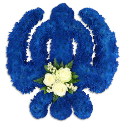 A large Sikh Khanda funeral arrangement stands out boldly against a stark white backdrop, its iconic silhouette rendered in a sea of deep royal blue petals. The familiar elements of the symbol - the central double-edged sword, the embracing circle of the chakkar, and the protective sweep of the two kirpans - are all fully covered with densely massed chrysanthemum florets, tucked so neatly that the surface appears smooth yet gently textured. The blue colour is intense and even, reminiscent of ceremonial cloths seen at Gurdwara gatherings near Grove Park, and it carries a quiet gravity fitting for a time of mourning and remembrance. At the base of the central sword, where the eye naturally comes to rest, a softer, lighter detail has been added. Three white roses, perfectly formed and just at their peak, are nestled together in a tight grouping. Around them, fine sprays of baby's breath create a lace-like fringe, and small pieces of glossy green foliage provide subtle contrast without overwhelming the purity of the white blooms. This modest cluster sits slightly raised from the blue background, catching the light and drawing the viewer into a moment of reflection. The tribute looks carefully constructed, the edges crisp and symmetrical, as though a skilled florist has shaped it for a Sikh funeral or memorial service serving families in and around Grove Park. The composition speaks of faith, respect, and the enduring bond of family, a floral Khanda designed to rest beside a casket, at the front of a chapel, or within a Gurdwara as prayers are offered and stories are shared.