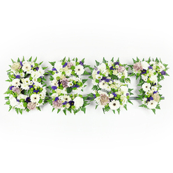 This comforting floral tribute spells DAD in bold capital letters, each letter a woven tapestry of whites, soft purples and fresh greens arranged on a pristine white backdrop. The composition centres on velvet chrysanthemums and large ivory gerbera heads, their rounded faces opening like quiet, earnest notes; alongside these are creamy, pastel coffee roses - a gentle, grounded blush - and clipped lisianthus that add a delicate, ruffled edge. Sprays of violet statice and mauve filler flowers thread through the letters, giving a restrained lift of colour that reads as warmth and affectionate memory. The letters' edges are lined with lively fern fronds whose serrated green adds structure and graceful movement, while clusters of green button chrysanthemums nestle into the interiors to introduce depth and a fresh, garden-like coolness. A dark grey base is visible in small sections, the discreet frame that allows each letter to hold a clear, respectful silhouette. The air around this arrangement suggests the soft perfume of roses and carnations, steady and consoling in tone. As the team at Grove Park Florist who made this piece, we picture it placed beside a service order or at the head of a memorial, offered to families from Grove Park station to Chinbrook Meadows who seek a personal, handcrafted way to say goodbye. The work combines precise lettering with tender floral detail so that the message - DAD - is both unmistakable and suffused with gentle care, perfect for a funeral, wake, or remembrance gathering in the local community.