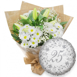 Captured in clear, neutral light, this photograph presents a graceful white bouquet alongside a refined silver anniversary balloon, set against a simple white backdrop. The bouquet on the left is lush with white chrysanthemum blooms that resemble cheerful daisies, each flower featuring a neat ring of petals and a round, golden-yellow centre that adds a gentle warmth to the arrangement. Among them stand elongated white lily buds, their sculpted forms mostly closed, with the slightest touch of pale green tracing the outer petals, poised as if they will open slowly over the coming days. Threaded delicately between the larger flowers are fine sprigs of white baby's breath, creating a filmy layer of texture that softens the shape of the bouquet and gives it a dreamy, romantic quality familiar to those who enjoy quiet celebrations in Grove Park's leafy avenues. Dark green foliage peeks out from behind the blossoms, some leaves broad and glossy, others more slender, all contributing depth and a sense of freshness. The stems are bundled securely, first enclosed in a clear cellophane sleeve for protection, then wrapped in rustic brown kraft paper that is folded in smooth, overlapping layers and tied at the base, making the bouquet appear ready for local delivery to a riverside home or cosy flat near Grove Park station. To the right of the flowers rests a round silver foil balloon with a subtle, crinkled sheen. Its design features intricate scrollwork and delicate floral patterns in a slightly deeper silver, circling a graceful "25th" written in script at the centre. Behind the main lettering, soft grey "Happy Anniversary" phrases repeat across the surface. Together, bouquet and balloon evoke a Silver Anniversary celebration that is elegant, tender, and quietly joyful.