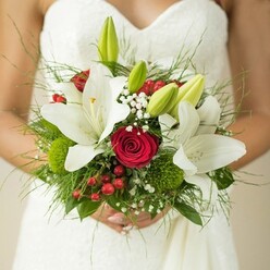 This striking Grove Park bridal bouquet is a study in emotion and floral artistry, perfectly suited for wedding mornings in the heart of West London. The openness of each white lily, their petals lace-edged and radiant, projects innocence-much like the soft promise of a new day on Park Road. Amidst them, rich red roses are entwined, their sultry, tightly bound petals pulsing with understated passion and romantic history cherished along the Thames path. Generous accents of glossy red hypericum berries and clusters of mossy green dianthus add intrigue and tactile dimension, reminiscent of Grove Park's serene, leafy corners. Wisps of baby's breath float airily, imparting a sense of dreams and quiet wishes, like gentle wind threading through Chiswick's meadows. The cool, feathery touch of finely arranged foliage cradles the bouquet, giving a sense of calm and grounding. The composition is held lovingly in the bride's hands, a visual and emotional centrepiece against her intricately textured gown. Each flower, bud, and berry, chosen for freshness and symbolic resonance, transforms the bouquet into a talisman of hope, devotion, and the vibrant beginnings that define Grove Park's wedding celebrations. Offering both visual splendour and a subtle fragrance that lingers softly, this arrangement is designed to weave itself into the tapestry of cherished memories, crafted with local care and expertise.