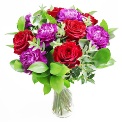 In this scene, a thoughtfully composed bouquet of rich red roses and opulent purple peonies rests in a clear glass vase, as if proudly displayed on a Grove Park dining table ready for an evening gathering. The red roses are open and expressive, their velvety petals spiralling outward to form generous cups that suggest affection and deep emotion. Nestled closely alongside them, the purple peonies are lush and rounded, densely layered with ruffled petals that lend softness and a luxurious, almost cloud-like texture. Encircling the central blooms is a generous halo of greenery, with broad, glossy leaves and airy sprigs of eucalyptus threading between the flowers, their soft, silvery tones and feathery silhouettes adding elegance and a sense of movement. The interplay of colour-deep crimson, regal purple, vibrant green, and cool eucalyptus-feels intentional and refined, the work of a florist familiar with the understated style often favoured in Grove Park homes near Chiswick Bridge and the quiet tree-lined streets. Through the vase, the neatly cut stems are clearly visible, criss-crossing gracefully in fresh water that sparkles under the light, reinforcing the impression of freshness and craftsmanship. This bouquet seems perfect for same-day delivery to celebrate an anniversary, a special birthday, or a personal achievement, perhaps arriving at a doorstep near the local station or one of the riverside roads. Even without scent, the image suggests a gentle perfume of roses and leafy greenery, the kind of fragrance that would subtly fill a room and make every glance at the bouquet a small moment of pleasure and pride.