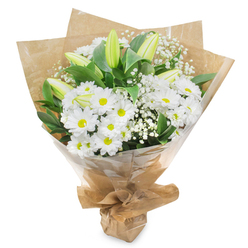 Set against a seamless white background, this elegant white and green bouquet appears as if freshly finished on the counter of a small Grove Park florist, ready to be carried out towards the river. The heart of the arrangement features a generous cluster of daisy-like white chrysanthemums, their petals fine and abundant, fanning out from vivid yellow-green centres that bring a subtle touch of brightness. Packed closely together, these blooms create a plush, cushiony effect that feels soothing and calm, well-suited to times of reflection and remembrance. Among the daisies, several upright lily buds rise with quiet poise, their elongated, tapered forms cloaked in soft green that gradually blurs into creamy white at the tips. Still firmly closed, they promise future blossoms and a gentle fragrance that will unfold in the days ahead, echoing the slow, steady movement of boats along the nearby Thames. Delicate sprigs of baby's breath thread through the bouquet, their tiny white blossoms scattered on slender stems, adding an airy, mist-like quality that softens the structure. Around the outer edges, glossy dark green leaves spread and overlap, framing the white flowers and grounding the design with a natural, garden-like feel reminiscent of the greenery lining Grove Park's quieter residential streets. The stems are neatly gathered and wrapped in softly crinkled brown kraft paper, which forms a warm, rustic collar around the flowers. Over this sits a clear cellophane layer, slightly reflective, offering protection while allowing the intricate details of the bouquet to remain visible. The base is cinched and tied into a compact, conical shape that sits comfortably in the hand. The overall impression is of a pure, understated sympathy bouquet, perfect for offering solace, conveying condolences, or gently brightening a calm corner of a home in Grove Park.