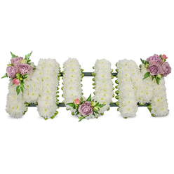 A lovingly made memorial arrangement spells out the word "MUM" in crisp capital letters, each letter sculpted from a dense carpet of white chrysanthemums that creates a plush, cloud-like surface against a clean white background. The white blooms register as an emblem of purity and peaceful remembrance; their tiny petals overlap like soft paper feathers, catching light to form a luminous, even field. Three clusters of pastel roses - muted lavender and gentle pink buds and opens - punctuate the all-white composition: one graces the upper left of the first 'M', another nestles in the rounded dip of the 'U', and a final cluster adorns the upper right of the last 'M'. The roses' velvety texture and faint sweet scent soften the arrangement's geometry, while varied greenery, including narrow fern fronds and fresh lime-green leaves, provides contrast, depth and a natural silhouette.A dark green structural base, possibly ribbon-wrapped or moss-covered, is partly visible beneath the blooms, offering both support and a low-contrast frame that keeps the letters substantial and unified. This thoughtful sympathy tribute reads as a quiet poem to a mother: composed, respectful and intimate, intended for use at a funeral service, wake or graveside. As a local florist familiar with Grove Park and neighbouring Downham and Chinbrook Meadows, we craft such pieces to convey comfort and enduring love, designed to sit gracefully in a church or on a memorial plinth while allowing mourners room for quiet reflection.