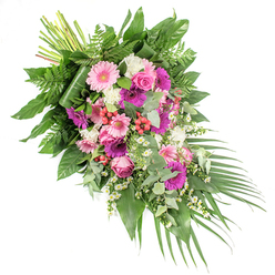 A graceful, asymmetrical funeral spray is arranged diagonally across a white backdrop, beginning in a full cluster of stems at the upper left and tapering into a soft cascade of greenery at the lower right. At the centre of the composition, generous gerbera daisies in two striking tones-blush pink and deep fuchsia-stand out, their flat, radiating petals catching the light and drawing the eye. Nestled between these bold blooms, pink roses with elegantly coiled petals provide a more traditional, romantic note, symbolising love and remembrance. Surrounding them, mounds of fluffy white flowers, reminiscent of miniature carnations or chrysanthemums, break up the stronger colours with gentle, cloud-like patches. Throughout the spray, small white daisy-shaped filler flowers punctuate the greenery, their simple shapes and golden centres adding an informal, garden-like charm. Scattered clusters of bright red hypericum berries bring textural contrast and pops of deeper colour, echoing the emotional intensity of farewell. Supporting all of this is an abundant array of foliage: broad, glossy dark green leaves give strength and depth, fine-textured ferns soften the outline, and rounded eucalyptus leaves in silvery green introduce a contemporary feel and a hint of refreshing fragrance. From the lower right, long palm leaves sweep outward, emphasising the movement and diagonal line of the design. The visible stems at the top hint at the careful handwork behind the arrangement. This kind of refined spray is typical of tributes prepared for funerals and memorials in Grove Park, a fitting choice for families seeking a heartfelt floral expression at local services along the leafy streets and near the riverside.