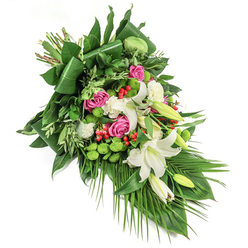 In this dignified, sweeping funeral spray, the rich variety and harmony of the blooms reflect the peaceful rhythm of Grove Park itself. Central to the design are pure, trumpet-shaped white lilies, some radiating their golden stamens, others still tightly coiled, symbolizing hope and remembrance. Paired with these, plush pink and deep fuchsia roses unfurl their petals, infusing the piece with warmth and compassion. Delicate white spray carnations and ruffled miniature blooms soften and fill the spray, while vibrant green button chrysanthemums cluster in rounded bursts, their freshness echoing the verdant breathing spaces near Staveley Road. Dotted within are brilliant red hypericum berries, offering lively contrast to the arrangement's predominant greens. The abundance of foliage-broad, glossy dark leaves, meticulously folded structural lines, lighter wispy sprigs, and graceful palm fronds-anchors the bouquet, providing depth and natural elegance. Each flower is caught in gentle light, highlighting its colour and velvety texture. Designed by Grove Park Florist for moments of tribute and reflection, this spray is ideal for funeral services, memorials, or sending heartfelt condolences throughout Grove Park and local communities, honoring cherished memories with every carefully chosen bloom.