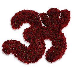 A reverent floral rendering of the sacred Om symbol, lovingly formed from deep red chrysanthemum blooms, each densely packed to create flowing strokes and rounded contours. The petals present a velvety garnet tone that shifts subtly in the light, while tiny bright green disk florets at the centre of many buttons give a delicate, organic punctuation to the otherwise monochrome field. Photographed on a stark white backdrop, the crimson Om holds a quiet intensity; its compact clustering of blossoms creates a plush, tapestry-like surface whose texture invites the eye to travel along every curve. As a florist who has arranged sympathy and remembrance pieces across Grove Park and the surrounding neighbourhoods, I sense in this composition both offering and shelter-the form reads like a visual prayer, a crafted emblem of solace meant to occupy a calm, contemplative space. The soft, diffused shadow beneath gives the symbol a slight elevation, as if lifted off the page, and the cool studio light enhances petal detail without harshness, preserving the arrangement's gentle dignity. Imagine the faint, comforting, earthy scent of fresh chrysanthemums mingling with the hush of a chapel or community room near Chinbrook Meadows; the piece functions as both art and ritual, suitable for memorial observances or quiet ceremonies. Skill and restraint are evident in the evenness of the packing and the graceful balance between structure and living texture-an offering that reads as solemn, attentive, and deeply respectful.