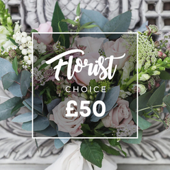 This bouquet reads like a moment of calm held in the hand: soft blush roses form the central chorus, their petal-rich heads opening slowly into warm, romantic cups. Interspersed are bright white berries-snowberry or hypericum-that add crisp, luminous punctuation against the roses' softness. Cool, rounded eucalyptus leaves weave through the bouquet in dusty blue-green tones, their texture smooth and slightly silvered, releasing that characteristic, soothing scent when moved. Tiny white fillers, perhaps waxflower, create a delicate, meadow-like haze around the larger blooms, while occasional deeper pink or burgundy accents add gentle shadow and visual intrigue. Slender, upright flower spikes at the edges provide structure and a hint of formality balanced by the loose, garden-picked styling. The stems are hand-tied and finished with a cream satin ribbon, the knot tucked neatly to emphasise the artisan touch. A beautifully carved, light-coloured stone backdrop sits softly blurred behind the arrangement, and a simple white rectangular overlay contains flowing script that reads "Florist," "CHOICE" beneath it, and the clear price, signalling a trusted, curated option. As a local florist well known in the area, Grove Park Florist would describe this as the kind of bouquet chosen for quiet celebrations-an anniversary, a new-home welcome, or a thoughtful get-well-sent with care to Grove Park, Lee Green, or nearby Hither Green. Captured in soft daylight, the bouquet radiates refined simplicity and the fresh, reassuring scent of eucalyptus and roses.