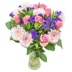 As I craft this arrangement at Grove Park Florist, I find myself enchanted by the luminous interplay between blush-pink gerberas and classic, well-formed pink roses-echoing the subtle shades of blossom along Grove Park Terrace in early spring. The soft mingling of pinks creates a watercolour-like effect, while pops of rich purple statice punctuate the design with playful energy. Cool, fresh leaves underpin the bouquet, moist and invigorating to the touch, grounding the ethereal quality of the blooms above. The composition feels bright and optimistic, like a new dawn over nearby Dukes Meadows, and is presented in a clear glass vase that adds a touch of classic restraint. Suitable as a cheerful get-well message for a loved one or a stylish centrepiece for a sun-drenched living room near Fauconberg Village, this arrangement is a testament to meticulous craftsmanship and a love of artistry. Every detail, from the dewy greenery to the luminous colours, is selected to instil joy and comfort-a heartfelt reflection of Grove Park's vibrant community.