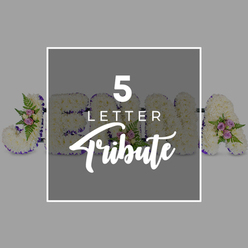 A carefully styled studio photograph shows a customised five-letter floral tribute for a funeral or memorial, laid out on a clean, light grey surface that makes every colour and contour stand out. Five individual letters stretch horizontally across the frame, each one entirely clad in tightly packed white chrysanthemums so that no base is visible, just a plush blanket of cool, velvety petals. Encircling the perimeter of each letter is a deep purple satin ribbon, smoothed and folded to trace the shapes with precision, adding contrast and a sense of formality that feels fitting for a final farewell. Interspersed along the letters are small, artful groupings of flowers and foliage: delicate pale pink and lilac-mauve spray roses nestle into the chrysanthemums, surrounded by fresh green leaves and airy strands of fern, their subtle colours flowering softly against the white. The arrangement hints at the name "JOHNA," with a clear "J" at the far left and an "A" at the far right, while the middle letters are partially hidden beneath a central overlay, symbolising the flexibility to spell any five-letter name or word. Over the centre of the tribute rests a gentle grey square, edged with a white border and inscribed with "5 LETTER Tribute" in crisp white type, combining a clean sans-serif font with a flowing cursive script for the final word. The balanced composition and even lighting create a sense of peace and contemplation, evoking the type of thoughtful letter tribute a family in Grove Park might have delivered by Grove Park Florist to a service near Chinbrook Meadows, where the white blooms and purple edging mark a loving, personal goodbye.