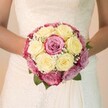 With a quiet grace emblematic of Grove Park weddings, this close-up reveals a bride clasping a bouquet that resonates with love and celebration. Creamy ivory roses mingle in round perfection with blush-pink and lilac-toned counterparts, reminiscent of the delicate hues found in the riverside parks around Grove Park and Chiswick. Airy clouds of white gypsophila drift among the roses, offering a touch of dreamlike softness, as deep green leaves peep out-evoking memories of picnics along the Thames Path. The arrangement rests gently in the bride's arms, her gown's lace-covered bodice and flowing skirt reflecting timeless bridal fashion. Soft, natural light skims the bouquet and the delicate stitching of the dress, drawing out every texture and curve. The background falls away in gentle blur, letting the floral artistry steal the scene. This bouquet-handcrafted by a florist who knows Grove Park's spirit-serves as both celebration and keepsake, inviting couples to imagine the possibilities for their own wedding journeys.