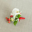 A carefully crafted boutonniere lies centered on a softly textured, light beige linen backdrop, the kind of neutral fabric you might see on a classic table in a Grove Park townhouse. The focal point is a pristine white Phalaenopsis orchid bloom, its broad, velvety petals gently unfurling in a calm, open shape. At the heart of the orchid, a delicate throat of creamy yellow and soft orange glows with warmth, drawing the eye inward and adding a hint of sunrise colour. Nestled closely around this central flower are clusters of tiny, cloud-like white baby's breath, their airy blossoms creating a misty halo that softens the composition and contrasts with the orchid's smooth surface. Along one side, a generous spray of glossy, round red berries adds a festive flash of colour, like polished beads catching winter light on Grove Park High Street. A few paler green, oval buds peek through the arrangement, suggesting freshness and new growth. Lush green leaves in varied shapes - some wide and pointed, others slim and elongated - weave between flower and berry, framing the design with natural richness. At the base, the stems are neatly gathered and wrapped in a vibrant red satin ribbon, tied in a small, firm knot with short, tidy tails that rest gently on the fabric. The lighting is soft and even, allowing the white, red, and green tones to feel calm yet celebratory. The whole piece suggests a refined buttonhole or small corsage, perfect for a winter wedding near Chiswick or a formal celebration in one of Grove Park's riverside venues, adding a quiet but memorable touch of nature to a lapel.