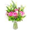 A luminous bouquet of deep pink roses and poised white lily buds sits in a clear glass vase, photographed against a bright white backdrop so every texture and colour reads clearly. Several large roses dominate the composition - their velvety petals unfurl in layers of fuchsia and blush, each curl catching a soft, diffused light that suggests early morning sun on a kitchen table. Interspersed are elegant white lilies, many held as tight, graceful buds and a few just beginning to reveal trumpet-shaped petals; the contrast between the rose's rounded softness and the lily's sculpted form gives the arrangement a composed, refined movement. Luxuriant green foliage fills the spaces between blooms, from broad glossy leaves that catch highlights to finer, lighter sprigs that provide airy depth; occasional darker burgundy or reddish-brown accent buds are tucked in, adding a subtle, grounding texture. The vase is simple and transparent with a gently tapered base; clear water shows neat green stems, anchoring the design and underscoring the flowers' freshness. As a florist who often prepares deliveries around Grove Park and nearby Lewisham, I imagine this arrangement brightening a small flat near the station or a sunlit table on the high street - it feels like a thoughtful birthday or anniversary gift that calms a room and lifts spirits. The overall effect is joyful and elegant without fuss: a carefully balanced study in colour, scent and form that reads as both celebratory and quietly intimate, ideal for someone who loves classic roses paired with the architectural presence of lilies.