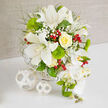 This luxurious bouquet sits poised on a spotless white surface, backed by a soft beige wall that could easily belong to a calm, light-filled home near Grove Park. At the heart of the composition, generous white Oriental lilies spread their satin petals wide, each blossom revealing speckled interiors and long stamens that lend a refined, almost architectural presence. Nestled close, a single yellow rose, with petals curled inward in a tight, buttery spiral, radiates gentle warmth and serves as a soft focal point, reminiscent of early evening light along the quiet Grove Park streets. Threaded through the design, tiny white flowers of baby's breath appear in frothy clusters, creating an airy veil between the larger blooms. Contrasting this delicacy, rounded, tufted green dianthus-those vivid moss-like balls-add an intriguing texture, bringing a contemporary twist to the classic wedding palette. Here and there, small clusters of glossy red hypericum berries emerge, like polished garnets, injecting moments of brightness that hint at festive celebrations or cosy gatherings in local riverside pubs. Light, feathery foliage in varying shades of green spreads outward, giving depth and a sense of freshness, as if the stems had been gathered from a well-tended garden overlooking the Thames. On the right-hand side of the bouquet, a cascade of white Phalaenopsis orchids tumbles gracefully, each bloom with luminous petals and a soft yellow centre, accompanied by slender green buds that promise future flowers. The arrangement is set in a subtle white woven basket, its texture mirrored by two smaller woven spheres placed on the table to the left. Crafted with the experienced eye of Grove Park Florist, this bouquet feels perfect for a wedding breakfast table, civil ceremony, or elegant anniversary celebration in the local area.