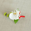 Set against a softly textured beige backdrop that recalls natural linen or burlap, this orchid boutonnière appears as though it has just been placed on a dressing table before a ceremony in Grove Park. The central orchid is a flawless white, its broad petals smooth and gently arched, surrounding a delicate heart flushed with pale yellow and tiny orange flecks that lend warmth without overpowering the design. Around the orchid, fine sprigs of baby's breath scatter in loose clusters, their miniature white blooms creating an impression of lightness, like a gentle mist drifting over a morning garden along Grove Park Road. Two vivid green buds sit to the left, likely small chrysanthemum or mum varieties, their compact, textured heads offering a crisp, contemporary counterpoint to the orchid's softness, while reinforcing the fresh, living quality of the piece. A single, deep green leaf peeks from beneath the main flower, adding a sleek, polished line of foliage that keeps the composition visually anchored and balanced. The stems are elegantly wrapped in vibrant red satin ribbon, the fabric wound smoothly and finished with a tidy bow that rests toward the right, its gleaming surface catching any available light and introducing a note of joyful celebration-ideal for weddings, proms, or black-tie events anywhere from Grove Park to nearby Chiswick and Hither Green. You can almost feel the contrast between the silky petals, the airy gypsophila, and the cool, satiny ribbon under your fingertips. This image conveys a sense of quiet anticipation: a handcrafted floral accent ready to be pinned onto a lapel, lending a touch of timeless romance and professional artistry to a carefully chosen suit or tuxedo.