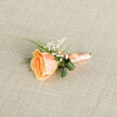 Presented from a gentle top-down angle, this boutonniere centres on a single apricot-peach rose whose petals form a tight, luminous spiral at the heart, gradually softening to creamier tips. The bloom's velvety texture catches the light in a way that suggests the warmth of a late-spring afternoon. Surrounding the rose, feathery sprays of white baby's breath (Gypsophila) scatter like tiny stars, offering an ethereal contrast that lifts the composition. Slender, bright green grass blades slice through the grouping and two darker, rolled leaves peek from behind, their curled architecture bringing a sculptural calm to the whole. The stems are carefully bound with a coordinating peach satin ribbon, tied into a neat bow whose satiny surface reflects a whisper of sheen; a small metallic pin is visible at the base where it will anchor to fabric. The boutonniere is laid on a finely woven ecru-linen background with a subtle cross-hatch texture that soothes the eye and amplifies the floral tones. Imagine this pinned to a groom's lapel or a prom jacket on a quiet street near Grove Park station or while walking past the park's nature reserve-the design reads as understated, elegant, and purposely tender. There is an olfactory memory in mind: the faint sweetness of rose, the clean green of freshly cut foliage, and the soft dusting of baby's breath. The overall effect is intimate and composed, a small ceremonial object crafted for meaningful moments.