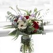 A celebration of contrast and grace unfolds in this floral design from Grove Park's local artisans. Deep red roses, plush and velvety, are offset by the creamy radiance of white gerberas whose dark centers hint at richness beneath the surface. Soft, lilac lisianthus-some unfurling, some still tight in bud-dance playfully through the bouquet, echoing the gentle cadence of breezes along Sutton Court Road. Silvery-green eucalyptus fans outward, lending an elegant wildness, their discoid leaves catching glimmers of daylight flooding into Grove Park homes. Sheltering the arrangement, sculptural deep green leaves gleam with vitality, accentuating the bouquet's abundant textures. Between the blooms, fluffy white filler flowers-each like the center of a daisy-provide soft dimension, nestled like pearls against velvet. The clear vase holds fresh stems in view, a picture of life and care. The subtle fusion of rose and eucalyptus aromas conjures both the sanctuary of local parks and the optimism of new beginnings. Meticulously designed for moments of gratitude, celebration, or quiet remembrance, this bouquet encapsulates Grove Park's heartfelt spirit and commitment to natural beauty.