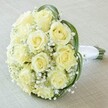 Presented from a close, angled perspective, this elegant bouquet springs to life with Grove Park charm-ideal for a wedding or anniversary in this welcoming neighbourhood. At its center, ten to twelve tightly furled roses in hues of creamy ivory unfurl, each petal vivid with freshness, embodying the promise of new beginnings. Gentle clouds of baby's breath weave through the arrangement, their airy clusters creating an ethereal, cloudlike texture that seems to hover over the softly blurred, light background. Broad, deep green leaves curve seamlessly around the roses, their lustrous surfaces offering a lush counterpoint to the pale blooms. Wrapped securely with a strip of pristine white satin, the stem handle emerges boldly to the right, practical and pleasing in the hand-ready to accompany a bride or serve as a gift on significant days. The whole bouquet, meticulously composed by Grove Park Florist and resting atop a cream-coloured tablecloth, shines with romance, sophistication, and the quiet confidence that makes local celebrations so memorable-not merely a bouquet, but a lasting tribute to Grove Park's sense of community and grace.