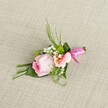 This delicately curated boutonniere, resting elegantly on a soft, neutral linen surface reminiscent of Grove Park's welcoming interiors, presents a blend of charm and sophistication. At the center is a pristine pastel pink rose, spiralled and fresh, emanating gentle beauty with a gradient from deep blush to palest pink at its ruffled edges. Tucked next to it, a light peach alstroemeria opens in a modest fan, its yellow-flecked petals adding warmth and a whisper of exotic detail. Tiny clouds of white baby's breath cluster nearby, making the richer greens of the miniature cushion mums and assorted foliage-both slender and broad-stand out with lush vibrancy. An expertly folded broad leaf grounds the design, while a wide, glossy fuchsia satin ribbon wraps and bows around the stems, glimmering with festivity. The textured backing in shades of off-white enhances the sense of freshness and care, each element thoughtfully placed to create harmonious balance. Evoking the sense of special occasions celebrated across Grove Park, from riverside gatherings to elegant weddings, this boutonniere is the perfect accessory to wear or cherish-a little symphony of romance and local artistry.