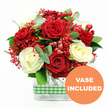 Against a seamless white backdrop, this red and white rose bouquet appears as a refined yet inviting centrepiece, the kind you might see brightening a sunlit room near Grove Park station. The focal point is a collection of deep red roses, opened to their full, velvety glory, each bloom layered with plush petals that convey warmth and passion. Interspersed among them are creamy white roses, their softly rounded petals adding brightness and a sense of calm elegance, so the overall effect feels celebratory without being overpowering. Woven between the larger roses are fine sprays of tiny, vivid red filler flowers, reminiscent of dyed gypsophila, which create a mist-like halo of colour and help link each bloom to the next. Clusters of glossy red hypericum berries punctuate the design, their smooth, rounded forms catching the light and lending a hint of seasonal charm perfect for winter celebrations, anniversaries, or romantic gestures across the Grove Park area. The flowers are nestled within a framework of fresh green foliage, including cool, slightly bluish eucalyptus leaves and other mixed greenery, giving the bouquet shape, movement, and a refreshing contrast to the red and white petals. All the stems are gathered into a contemporary rectangular clear glass vase, where the straight sides and visible stems introduce a clean, modern line that suits both traditional and modern interiors. Around the vase's midsection, a green and white gingham ribbon wraps securely, adding a touch of rustic, country-kitchen character that feels warm and familiar. In the bottom right corner of the image, an orange circular badge with crisp white lettering reads VASE INCLUDED, clearly showing that this lush arrangement arrives as a complete, ready-to-display floral gift, ideal for convenient local delivery by Grove Park florists.