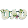 The photograph captures a beautifully composed DAD floral tribute, set crisply against a bright white background so that every petal and ribbon fold can be seen. Three bold, capital letters stand side by side on a subtle dark framework, each letter fully covered in pristine white chrysanthemums arranged so densely they form a thick, plush carpet of blooms. The flowers' small, rounded petals give a soft, comforting texture, evoking feelings of tenderness and remembrance. Outlining each letter is a rich emerald green satin ribbon, carefully pleated into a ruffled border that hugs every curve and edge, offering striking definition and a verdant, natural feel reminiscent of Grove Park's leafy streets and nearby riverside greenery. The first D is gently highlighted at its upper left with a neat cluster of white freesias and glossy green foliage, creating a point of interest and a delicate lift in height. From this accent, two long, elegant green stems sweep diagonally toward the central A, guiding the viewer's gaze. At the point where these stems meet the A, a focal spray of flowers has been arranged: two deep purple calla lilies, their sleek trumpet shapes and velvety petals surrounded by more white freesias and fresh greenery, bringing subtle drama and contrast. The last D balances the design with a smaller, harmonising spray of white freesias and foliage placed on its upper right curve. Overall, this tribute exudes calm dignity and heartfelt emotion, like the kind of memorial arrangement a family in Grove Park might choose to express enduring love and gratitude for their father during a final farewell.