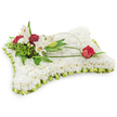 A gently rectangular pillow of flowers, the surface a plush sea of tiny white chrysanthemum blooms that read like soft, clouded fabric beneath the eye. The chrysanthemums are packed so closely their petals form a uniform, tactile sweep; you can almost feel the cool, velvety texture under a fingertip. Around the edge a pleated pale lime-green satin ribbon has been hand-folded into a delicate frill that catches a soft sheen from the studio light, giving the cushion a subtle, refined frame. The overall palette is spare and peaceful - white and soft green - and the arrangement rests against a clean white background that emphasises its serenity and quiet presence.
On the upper left a naturalistic vignette draws the gaze: two open white Oriental lilies, their broad petals unfurling to reveal warm yellow stamens, stand beside a neatly closed lily bud. Interspersed are clusters of deep burgundy spray carnations, their ruffled heads offering warm contrast and textural depth. Lush, varied green foliage - feathery fern fronds and broader glossy leaves - forms a verdant backdrop, while a slender arch of salal leaf or decorative wire curves from that cluster across the cushion like a gentle hand. The arch terminates on the right with a single deep red rosebud, just beginning to open, its velvety petals suggesting abiding love and respect. The lilies give a faint, sweet aroma that balances the composition's visual hush.
This traditional sympathy pillow, shaped and finished for a memorial or funeral, conveys comfort and reverence, the kind of understated, compassionate tribute you might choose for a service in Grove Park or a quiet chapel near Chinbrook Meadows.