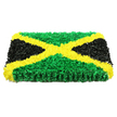 The image shows a beautifully composed Jamaican flag tribute crafted entirely from floral and petal-like textures, set against a bright white background that intensifies its bold, graphic impact. The tribute itself is rectangular and thick, resembling a plush, handcrafted panel. A vivid golden-yellow diagonal saltire dominates the composition, stretching from corner to corner. This cross is made from packed clusters of blossoms or fabric-style florets, their edges softly ruffled so the yellow gleams gently under the lighting, like evening sun catching the rooftops around Grove Park. This radiant X divides the piece into four distinct triangles. Above and below the cross, rich green blooms are pressed tightly together, forming lush, almost moss-like fields that suggest life, growth, and enduring roots. On either side, velvety black flowers or rosettes fill the remaining spaces, their matte texture introducing a sense of gravity and contemplation that feels fitting for a funeral or memorial service. The lighting is evenly balanced, enhancing the luminous contrast between green, yellow, and black, while fine shadows between petals hint at the care and time invested by an experienced local florist. From the side, the tribute's thickness is evident, showing it is mounted on a solid base designed for display near a coffin, at a graveside, or at a remembrance gathering along the river. This floral flag becomes a quiet yet powerful statement: a celebration of Jamaican heritage, a reflection of the multicultural community around Grove Park, and a comforting way for family and friends to honour a loved one's story, journey, and lasting place in their hearts.