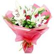 The bouquet in the image is a striking combination of pure white lilies and deep red roses, composed with a balance that feels both romantic and refined. At the centre, tall stems of Oriental lilies command attention, their trumpet-shaped blooms open wide so that the creamy white petals curve back elegantly, exposing pale green centres and six prominent stamens tipped with dark, rust-coloured pollen. Some lilies remain in bud, their smooth, elongated forms sheathed in soft green, suggesting freshness and future blossoms. Interlaced with these are rich red roses, many still in tight bud, others just parting at the edges to reveal their layered hearts, bringing warmth and depth to the design. Surrounding the flowers, lush greenery creates a supportive embrace: large, glossy leaves provide structure, while slender, grass-like fronds arc and weave through the bouquet, lending motion and a slightly wild, garden-inspired feel. The stems are gathered and cloaked in layers of bright pink, semi-transparent cellophane, folded into ruffled, voluminous shapes that flare out around the flowers like a celebratory collar. At the very base, a slim lime green ribbon is tied neatly, its smooth satin and vivid colour complementing the crisp foliage and adding a modern twist. The overall mood is one of joyful affection, making it easy to imagine this bouquet being prepared at Grove Park Florist and then carried along the leafy streets of Grove Park-perhaps delivered to a home near the station, presented as a birthday surprise by the river, or brought as a thoughtful thank-you gift after a gathering close to Chiswick House and Gardens.