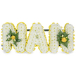 A carefully modelled three-dimensional tribute spells the word NAN in bold capital letters, each letter built from a dense snow-white carpet of small chrysanthemum florets to create a pillowy, tactile surface. Around every letter a tight, sunlit border of smaller yellow button-style blooms traces the contours, giving a bright, cheerful outline that lifts the composition against the pure white backdrop. The two outer N letters are finished with low clusters of deep, glossy green foliage tucked into the letter joints - broad camellia-like leaves or ruscus, slender fern fronds and a few tighter yellow rosebuds or button blooms that add a warm golden counterpoint to the white base. The central A is left quietly unadorned, its simple white face and yellow edge allowing the textures of the chrysanthemums to read clearly in soft studio light. A slim, discreet dark green support bar runs behind the top of the letters so the piece sits stably for viewing at a funeral or placed near a graveside. Up close, the scent is a soft, honeyed waft from the yellow buds paired with the fresh green note of cut foliage; under gentle overhead lighting the petals catch subtle highlights while shadows between florets give a pleasing three-dimensional depth. This arrangement reads as both respectful and gently uplifting, a contemporary classic of sympathy floristry meant to honour a much-loved Nan. As a local florist working in the Grove Park and Lewisham area, I picture this tribute set with quiet dignity near Grove Park station or at a family chapel close to Chinbrook Meadows, where its colours will carry a reassuring message of warmth and remembrance.