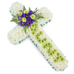 A dignified floral cross arrangement rests on a white background, its composition blending calm whites and fresh greens with a touch of deep purple, in a style well suited to funeral services around Grove Park. The foundation of the cross is a tightly packed bed of white chrysanthemums, their small petals layered in such a way that the surface appears soft and full, conveying an impression of purity and gentle comfort. Encircling this white base is a fine border of vivid green ribbon or foliage, tracing each arm and curve with a precise line that sharpens the silhouette and brings in a fresh, natural energy, reminiscent of the leafy walks near Grove Park and the Thames. Running down the centre of the vertical arm is a panel of lime green button chrysanthemums or similar blooms, their compact, rounded forms nestled together to form a smooth stripe that contrasts yet harmonises with the white. Draped lightly over this green section, thin strands or wires in a soft, pale green form a loose criss-cross pattern, adding an extra layer of texture that feels refined and contemporary. At the heart of the cross, where the arms meet, lies a rich cluster of deep purple lisianthus, their velvety, ruffled petals and dark centres adding depth, solemnity, and a sense of tender emotion. Interspersed among them, bright lime green flowers echo the vertical band, while sprays of dark green fern arch outward, introducing movement and a touch of wild, garden-like grace. This thoughtfully arranged cross offers a respectful and faith-led tribute, ideal for church, crematorium, or graveside ceremonies in the Grove Park area, expressing love, remembrance, and peaceful farewell.